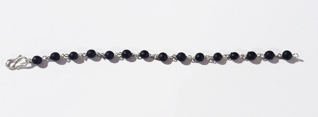 Black bead bracelet with silver links, worn on wrist