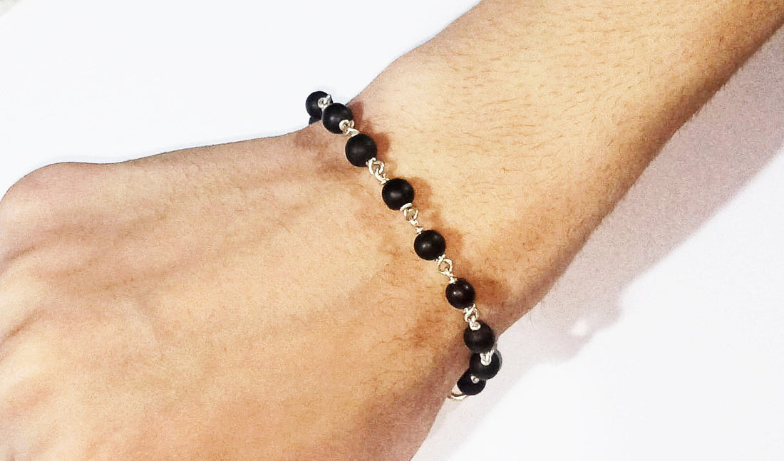 Black bead bracelet with silver links, worn on wrist