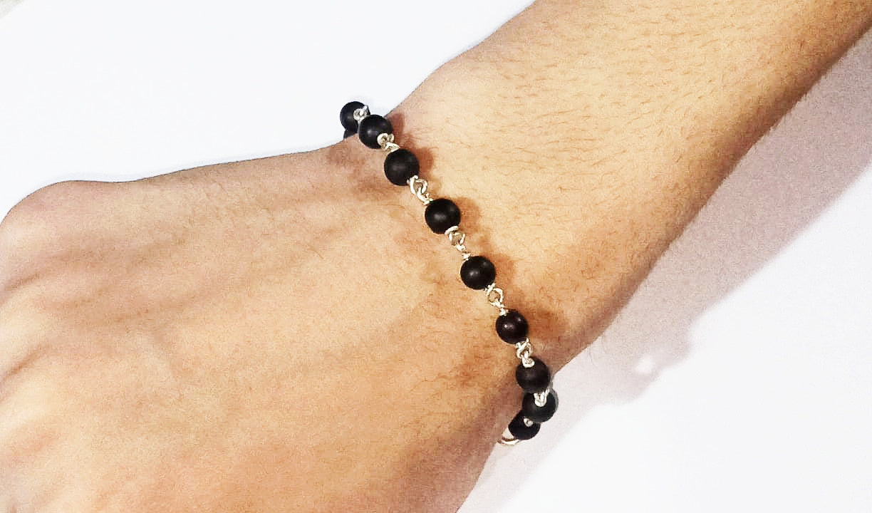 Black bead bracelet with silver links, worn on wrist