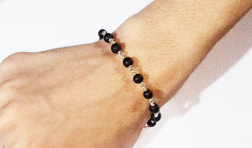 Black bead bracelet with silver links, worn on wrist