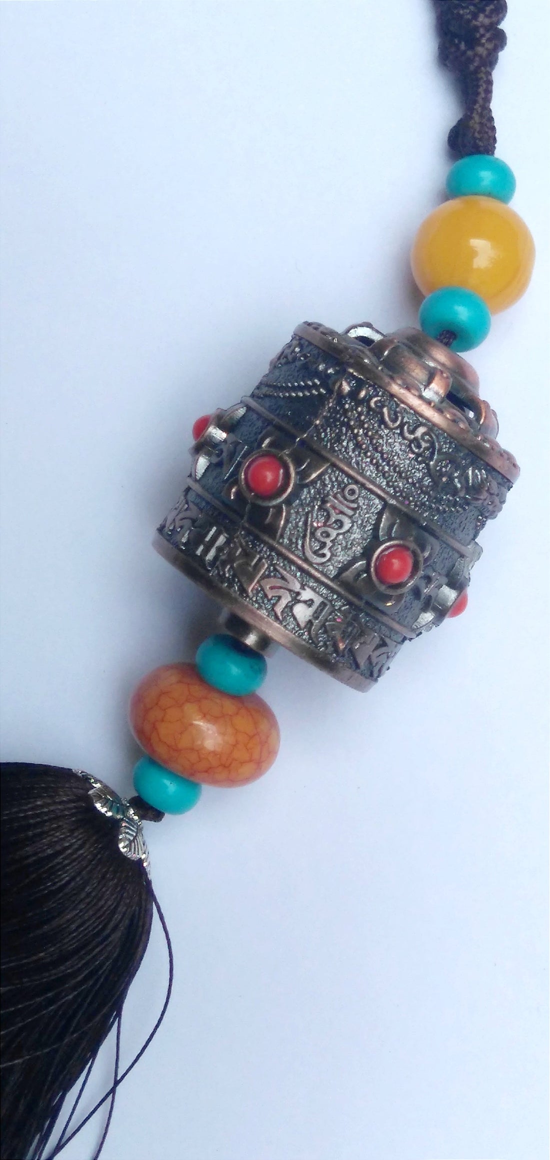 Prayer wheel hanging with carved metal cap, red cabochons, turquoise bead string, tassel