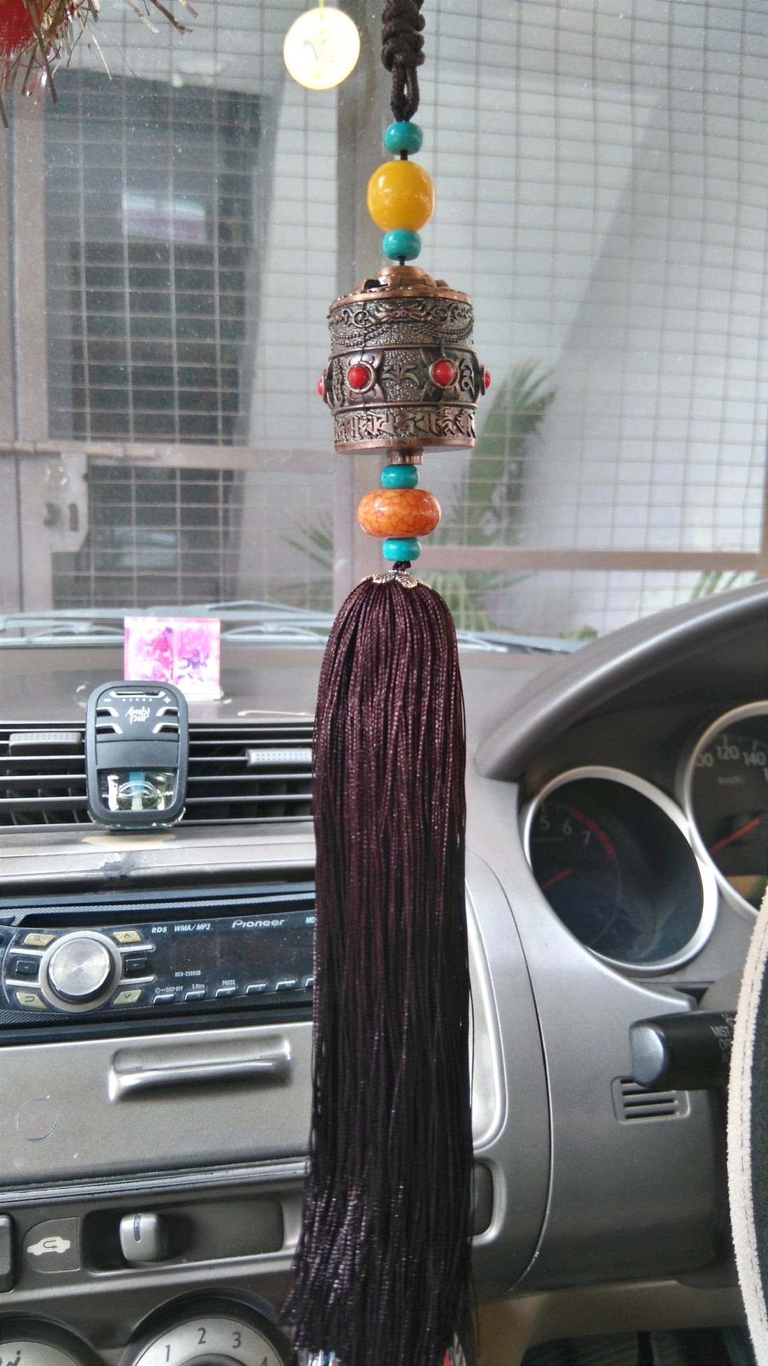 Prayer wheel hanging with carved metal cap, red cabochons, turquoise bead string, tassel
