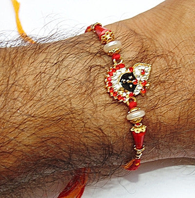 Krishna rakhi on wrist: red thread with gold accents, white beads, jeweled black face