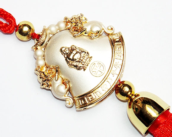 Close-up of golden bell pendant with laughing Buddha face and red cord beads