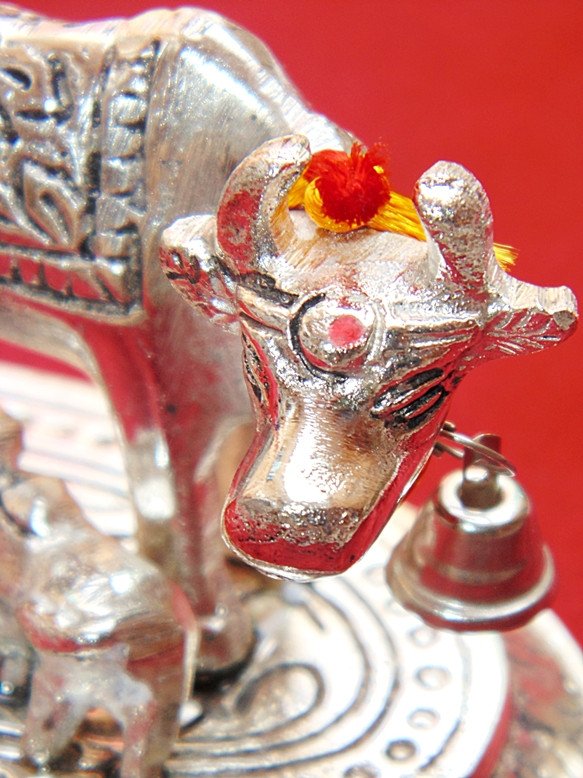 Close-up white cow head idol with red detailing, flower crest and small hanging bells