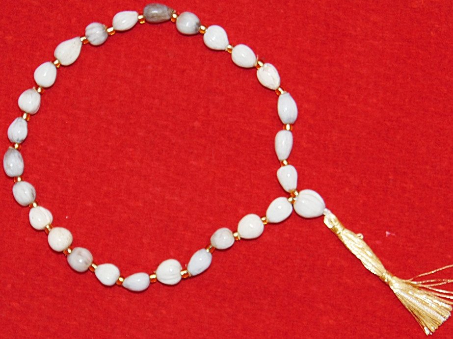 27+1 Vaijanti wrist mala with white oval beads, gold links, and tassel charm
