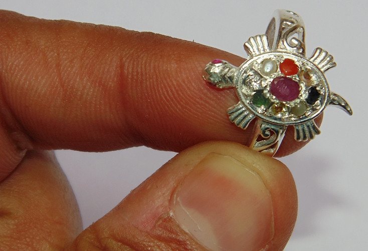 Tortoise ring detail: small red, pink, green and black stones on silver setting