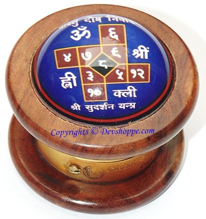Wooden Vastu compass with blue yantra center and metal-toned rim, angled view