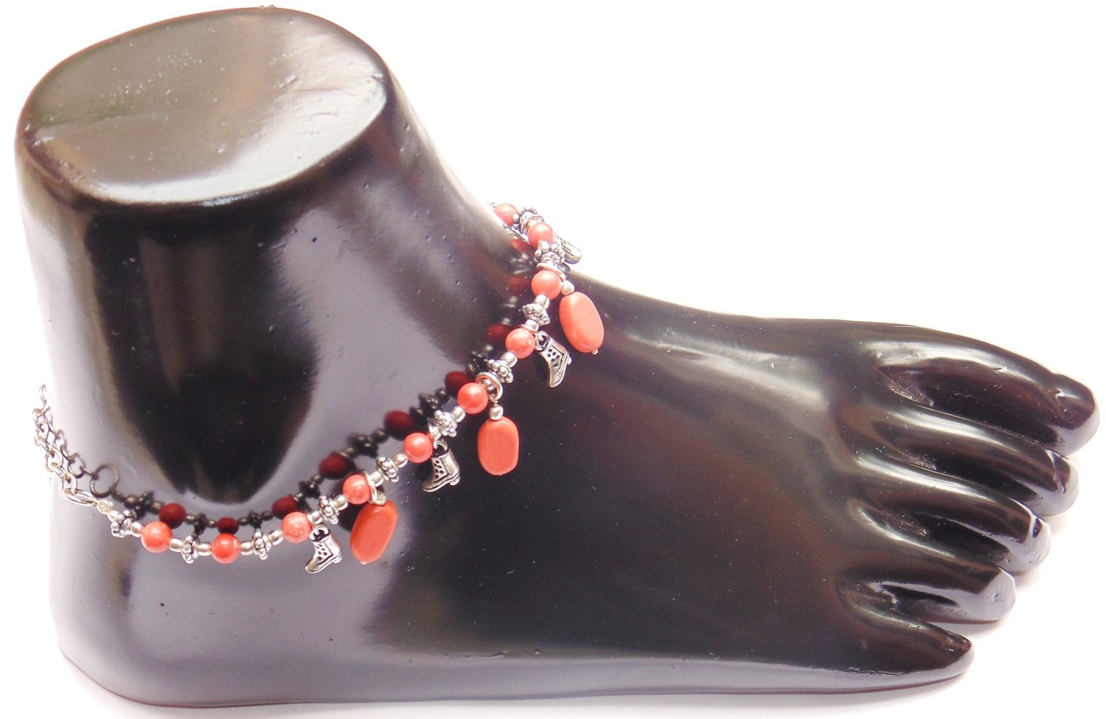 Orange beaded anklet with dangling charms and silver chain on a mannequin foot