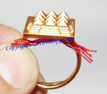 Adjustable brass pyramid ring with geometric gold-tone top, red thread tassel