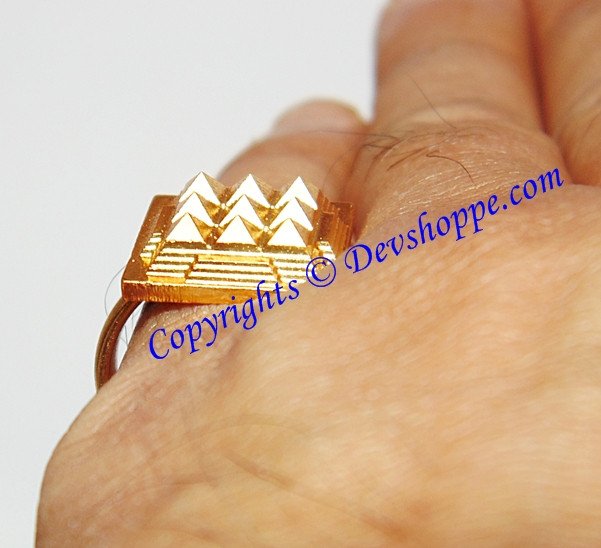 Golden brass pyramid ring on finger with square geometric centerpiece visible