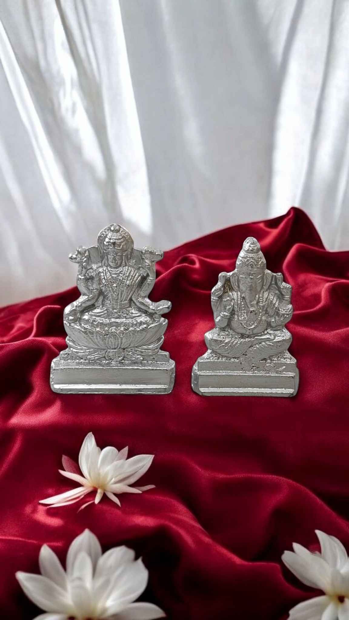 Silver Lakshmi and Ganesha statues with lotus flowers on red satin cloth