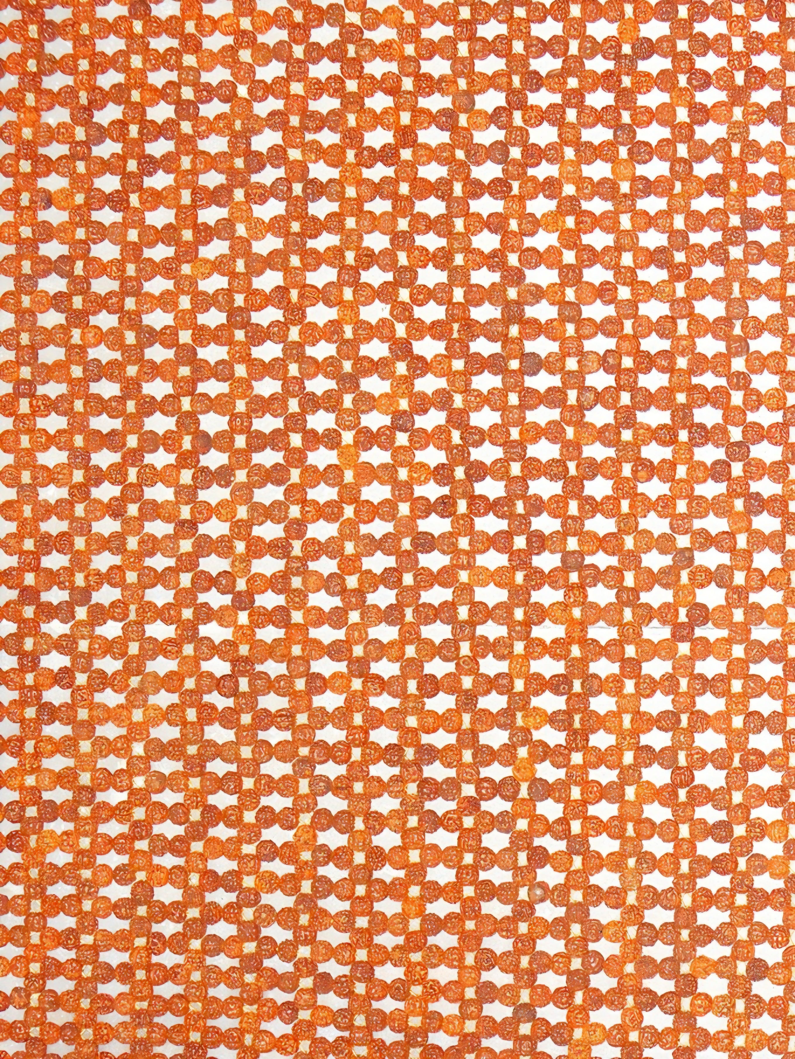 Close-up of orange rudraksha beads woven in a grid pattern