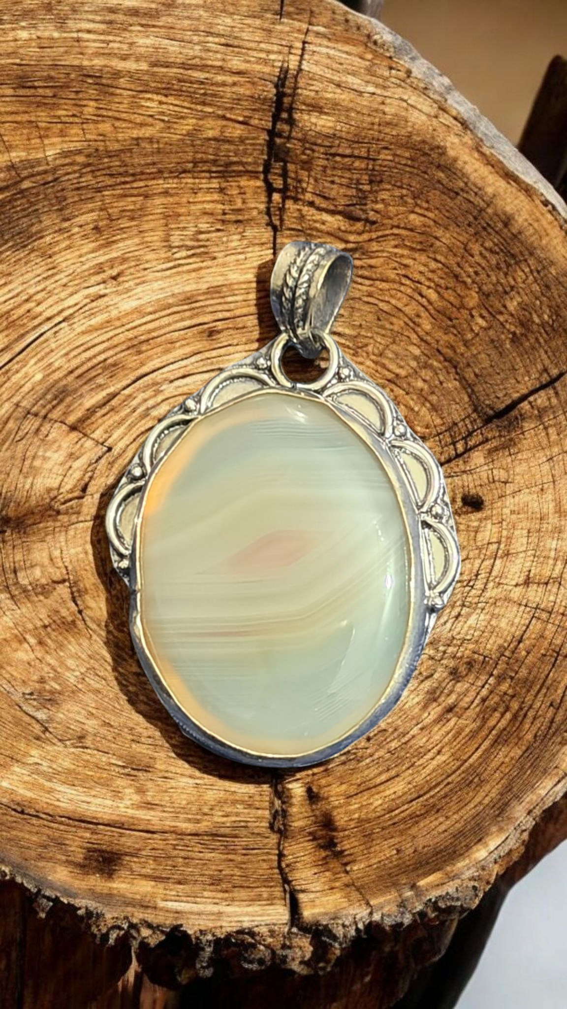 Oval agate pendant with pale green swirled stone in ornate silver frame