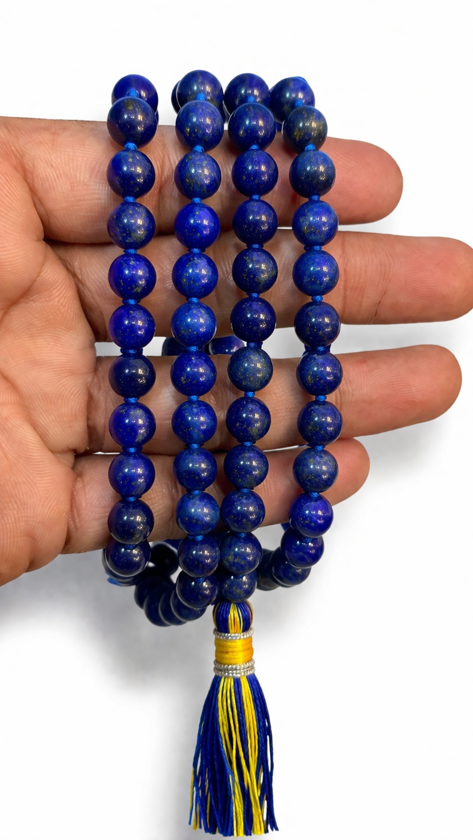 Lapis lazuli mala beads held in hand, blue round stones with yellow-and-blue tassel