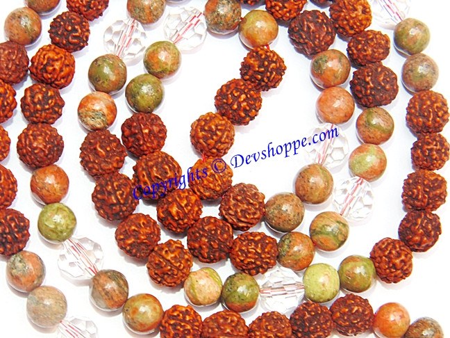 Close-up of red rudraksha beads and green mottled unakite beads on white thread