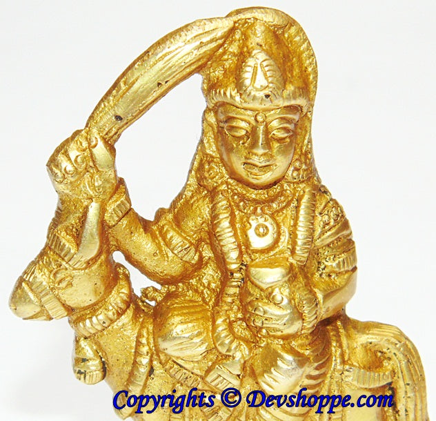 Shitala mata brass idol close-up, serene face, raised arm and ornate crown