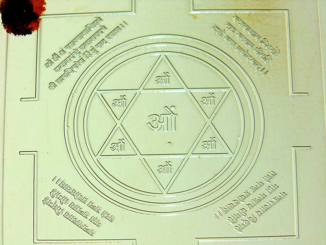 Brass yantra plate with circular protective geometry and centered triangle with ॐ symbol