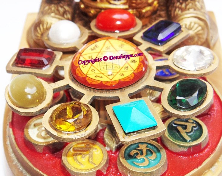 Close-up of yantra chowki with central yantra disc, red gem accents, colorful stones