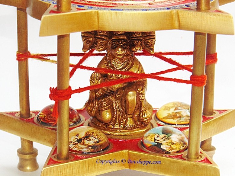 Five-faced Hanuman bronze idol with red ropes and four decorative circular tiles on stand