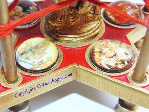 Bronze idol base above red platform with four circular deity prints on tiered stand
