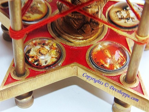 Red star yantra base with four circular deity medallions and bronze idol base beneath