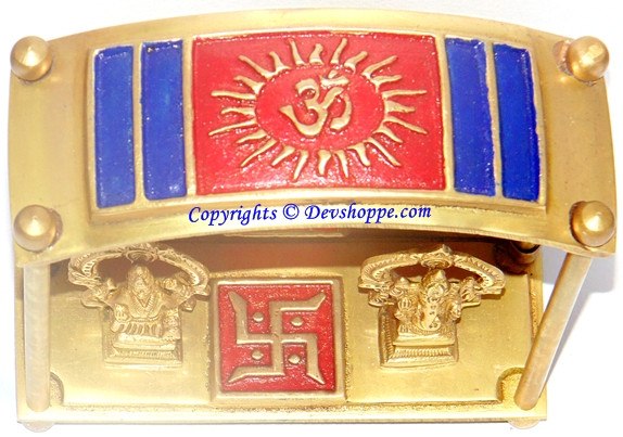 Brass yantra chowki base with red sun-like emblem and gold side deity motifs