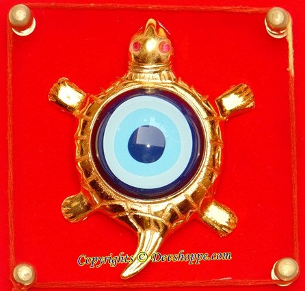 Close-up tortoise evil-eye hanging yantra, circular blue eye with gold shell detailing