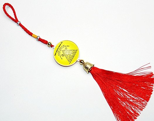 Yellow circular yantra tag on red cord with gold accents and red tassel